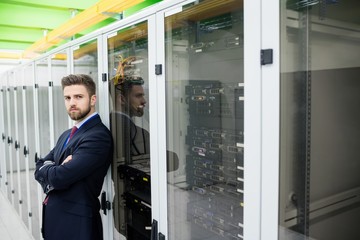 Fototapete - Technician standing with arms crossed in a server room