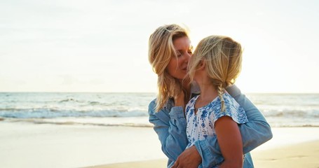 mother and daughter having fun playing on the beach at sunset