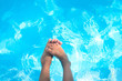 Child bare feet above blue water in swimming pool
