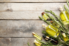 Bottles Of Coniferous Essential Oil And Rosemary Branches On Wooden Background
