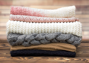 Wall Mural - winter knitted clothes stack on wooden background.