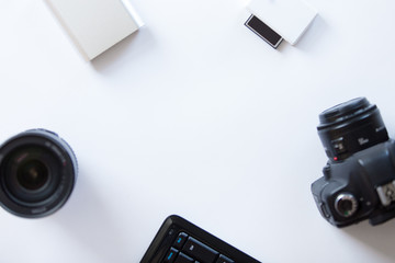 White desk with a professional camera and accessoires on it. Top view, copy space