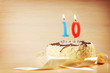 Birthday cake with burning candle as a number ten. Focus on the candle