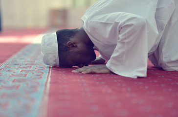 Wall Mural - African Muslim Man Making Traditional Prayer To God While Wearing A Traditional Cap Dishdash