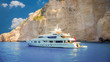 Luxury white yacht navigates into beautiful blue water near Zakynthos island. View from the top of a large white yacht at Navagio Beach.