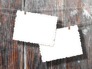 Two blank postcard frames hanged by pegs against dark brown wooden background