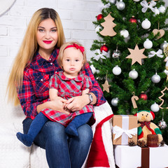 portrait of woman and her daughter sitting in decorated living r