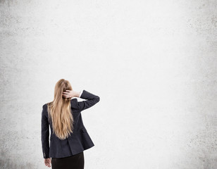 Wall Mural - Woman scratching head looking at concrete wall