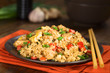 Hausgemachter gebratener Reis mit Gemüse, Hähnchen und Ei auf Teller mit Essstäbchen serviert (Selektiver Fokus, Fokus ein Drittel in das Gericht)
