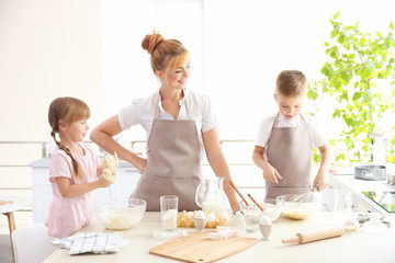 Canvas Print - Young mother and kids making dough in kitchen