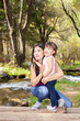 © 7stock - Asian Woman with her little daughter in the woods near the river standing on a log
