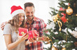 © Tijana - Young couple opening a Christmas present on a Christmas morning