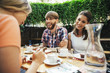 © Westend61 - Happy young couple with friend sitting outdoors having coffee and cake