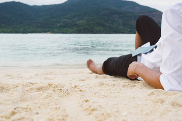 Businessman lying relaxing on sand beach look out to sea in holi