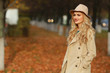 © lenblr - Beautiful elegant woman standing in fashionable beige hat in a park in autumn. free space.