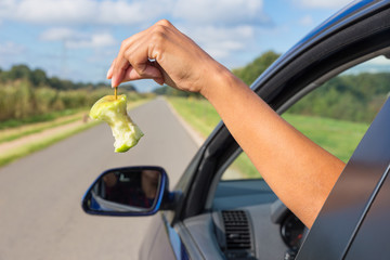 Female arm dropping apple core out car window