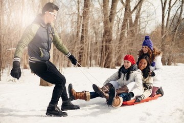 Group of friends enjoying pulling a sled in the snow in winter