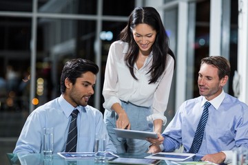 Wall Mural - Businesswoman discussing with colleagues over digital tablet