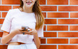 © dianagrytsku - Close up Young girl texting sms on brick wall background