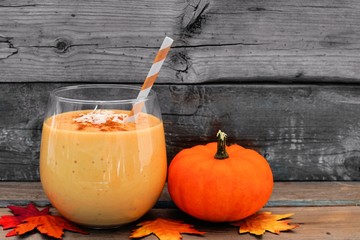 Wall Mural - pumpkin smoothie with coconut and cinnamon, scene on a rustic wooden background
