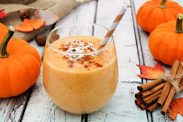 Wall Mural - autumn pumpkin smoothie with coconut and cinnamon, still life on white wood