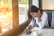 © sunti - Beautiful young woman Playing Mobile with morning coffee