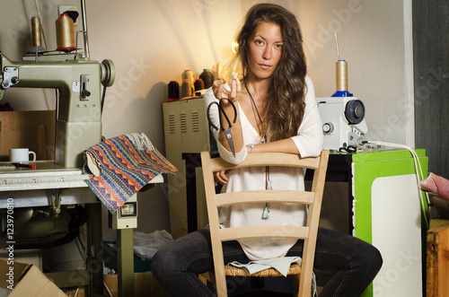 Fotografie, Obraz Beautiful fashion designer girl, posing in her workshop, holding scissors