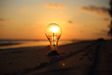 Electric Light Bulb And Sun At Beach Sunset Sky