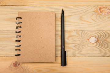 Brown note book with pen on wood background