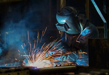 Worker With Protective Mask Welding Automotive Part In Factory