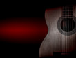 © YB - Part of a orange acoustic guitar on black background.