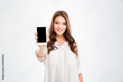 Fotografía Smiling woman showing blank smartphone screen isolated on white background