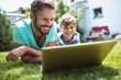 © WavebreakMediaMicro - Father and son using laptop in garden