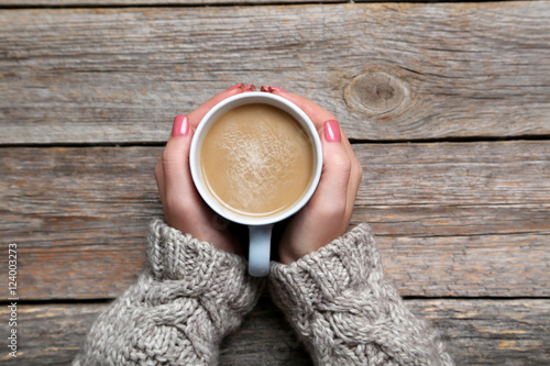 Fotografie, Obraz Woman hands holding cup of coffee on wooden table