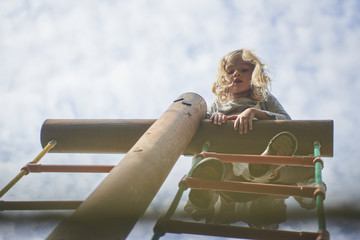 Wall Mural - Portrait of Happy little blond girl playing on a rope web playground outdoor

