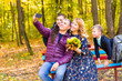 © satura_ - Smiling young family taking selfies on an autumns day