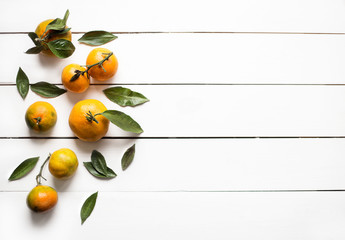 Fresh orange tangerines with leaves on white wooden table top view