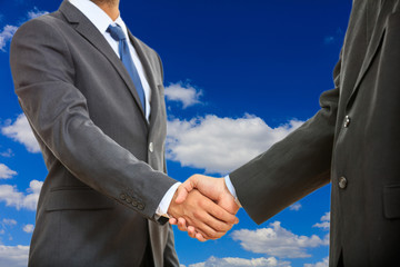 Handshake on blue sky background