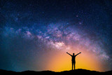 Fototapeta Kosmos - Landscape with Milky way galaxy. Night sky with stars and silhouette happy man on the mountain.