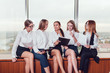 © kanashkin - Five business women sitting on the windowsill talk and study documents