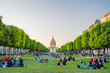 The National Residence of the Invalids and people sitting on a grass in Paris, France