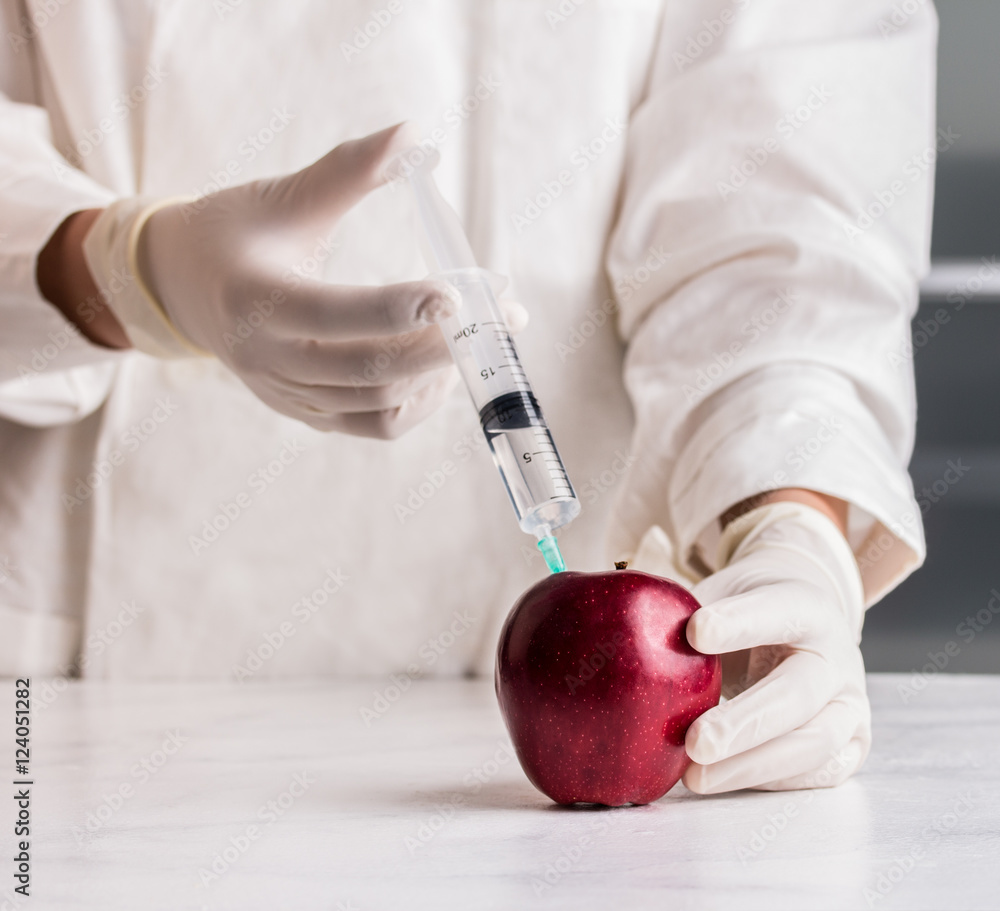 Scientist doctor injecting apple with syringe. Stock Photo | Adobe Stock