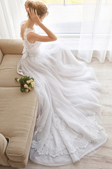 Wall Mural - Bride in beautiful dress with wedding bouquet sitting on sofa