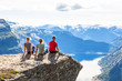© lkoimages - Happy friends relax on Trolltunga. People enjoy beautiful lake and good weather in Norway.