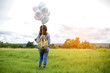 © sunti - Young beautiful woman with colorful balloons on a green meadow