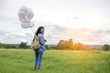 © sunti - Young beautiful woman with colorful balloons on a green meadow