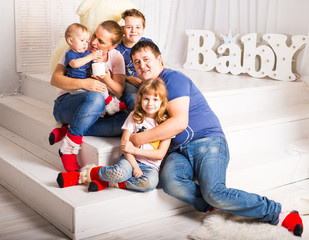 Happy family with 3 children sitting on floor of living room at home