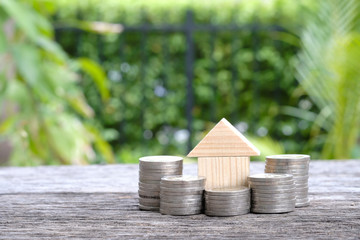  Women hand putting money coins stack growing with house and sunlight background. Business growth investment and financial concept ideas.