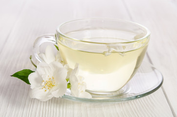 glass cup of tea with jasmine on the white wooden background