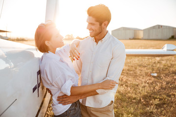 Happy couple on a honeymoon standing at the airplane field